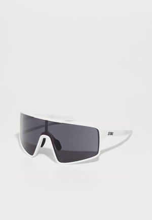 Lunettes de soleil blanches surdimensionnées avec des verres sombres. Fabriquées en plastique, elles présentent un design sportif et un logo bien visible sur la branche.