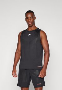 Top atletico senza maniche nero con logo, caratterizzato da un design testurizzato e una vestibilità ampia. Abbinato a pantaloni corti neri coordinati, anch'essi con dettagli testurizzati.