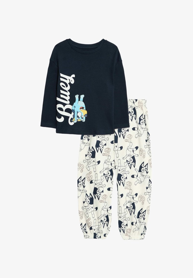 Dark navy long-sleeve top with "Bluey" graphic; cream pants featuring blue and black dog pattern and elastic cuffs.
