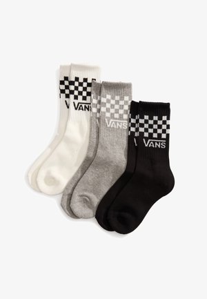 Quatre paires de chaussettes Vans en blanc, gris clair, gris foncé et noir, avec un motif à carreaux et un logo en haut. Matière en mélange de coton.