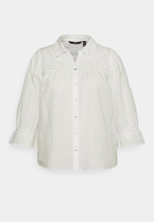 Biała bluzka zapinana na guziki z ażurową koronką na karczku i marszczonymi mankietami, z kołnierzykiem i rękawami o długości do łokcia.