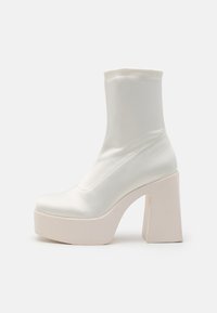 White satin ankle boot with a chunky, square heel and platform sole. Features a smooth texture and minimalistic design.