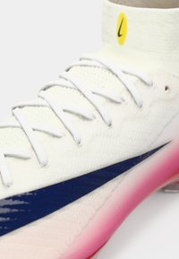 Witte sportschoen met een gestructureerd oppervlak, voorzien van een blauwe zijkant swoosh, witte veters en een gradiënt roze zool. Gele accenten bij de hiel.