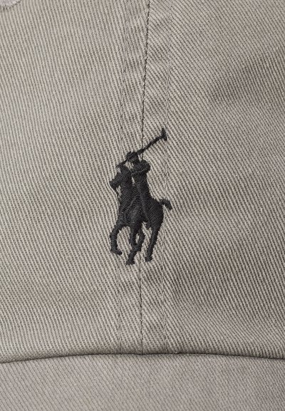 Schwarzes besticktes Logo eines Polospielers zu Pferd, der einen erhobenen Schläger hält, auf beigem strukturiertem Stoff, wahrscheinlich eine Kappe.