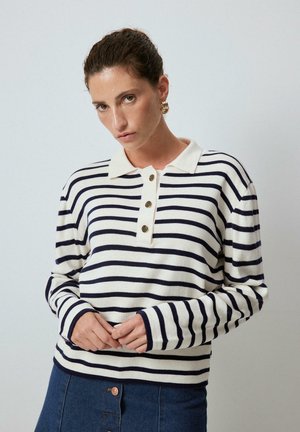 Striped pullover sweater with a cream base and navy stripes, featuring a collar and three-button placket. Made of soft, textured material.