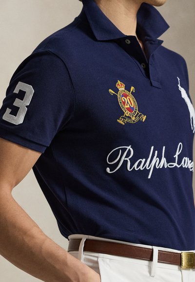 Tengerészkék galléros póló, hímzett logóval és a 3-as számmal az ujján, galléros nyakkal és fehér "Ralph Lauren" felirattal.