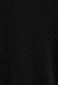 Zwarte gebreide stof met verhoogde stippen die in een ruitpatroon zijn gerangschikt.