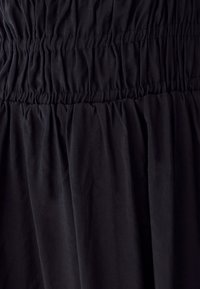 Black fabric dress featuring gathered details, with a textured appearance and a flowy silhouette. No additional patterns or accents visible.