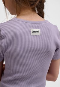 Lila ribbad kortärmad topp med rund halsringning och en etikett märkt "hummel PERFORMANCE" på övre delen av ryggen.