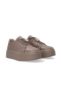 Braune Sneakers aus Kunstleder mit einer dicken strukturierten Sohle, die dekorative Kristallakzente an den Schnürsenkeln und ein rundes Zehendesign aufweisen.