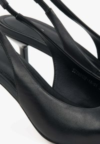 Zwarte leren hoge hakken met een gladde textuur, open neus en slanke bandjes. Heeft een smalle, hoekige hak en een minimalistisch ontwerp.