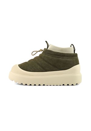 Zapatilla baja de ante verde oliva con suela gruesa beige, puño de tobillo acanalado y cierre de cordones con toggle, mostrada sobre fondo blanco.