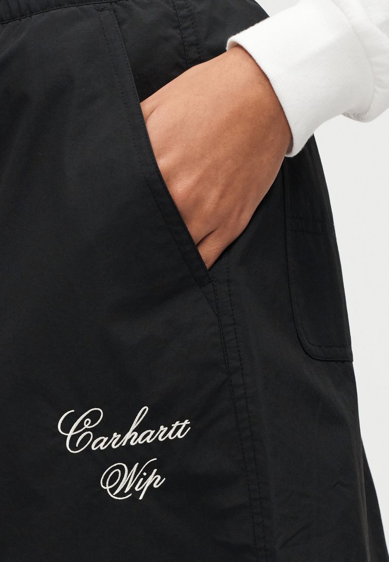 Black fabric pocketed shorts with Carhartt WIP embroidered logo in white. Smooth texture, relaxed fit, featuring side pockets.