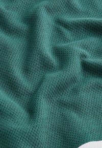 Texturiertes grünes Netzgewebe mit einem Diamantmuster, das Wellen und Falten zeigt. Der Stoff hat eine leichte, atmungsaktive Qualität.
