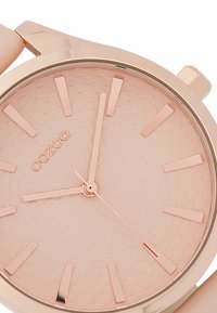 Montre ronde en or rose avec un cadran texturé en rose pâle, dotée d'index et d'aiguilles en or rose, ainsi qu'un bracelet lisse.