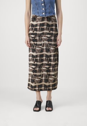 Denim crop topp med knappdetaljer, parret med et langt, mønstrede nederdel med abstrakte linjer i brun og krem, iført svarte slepp-sko.