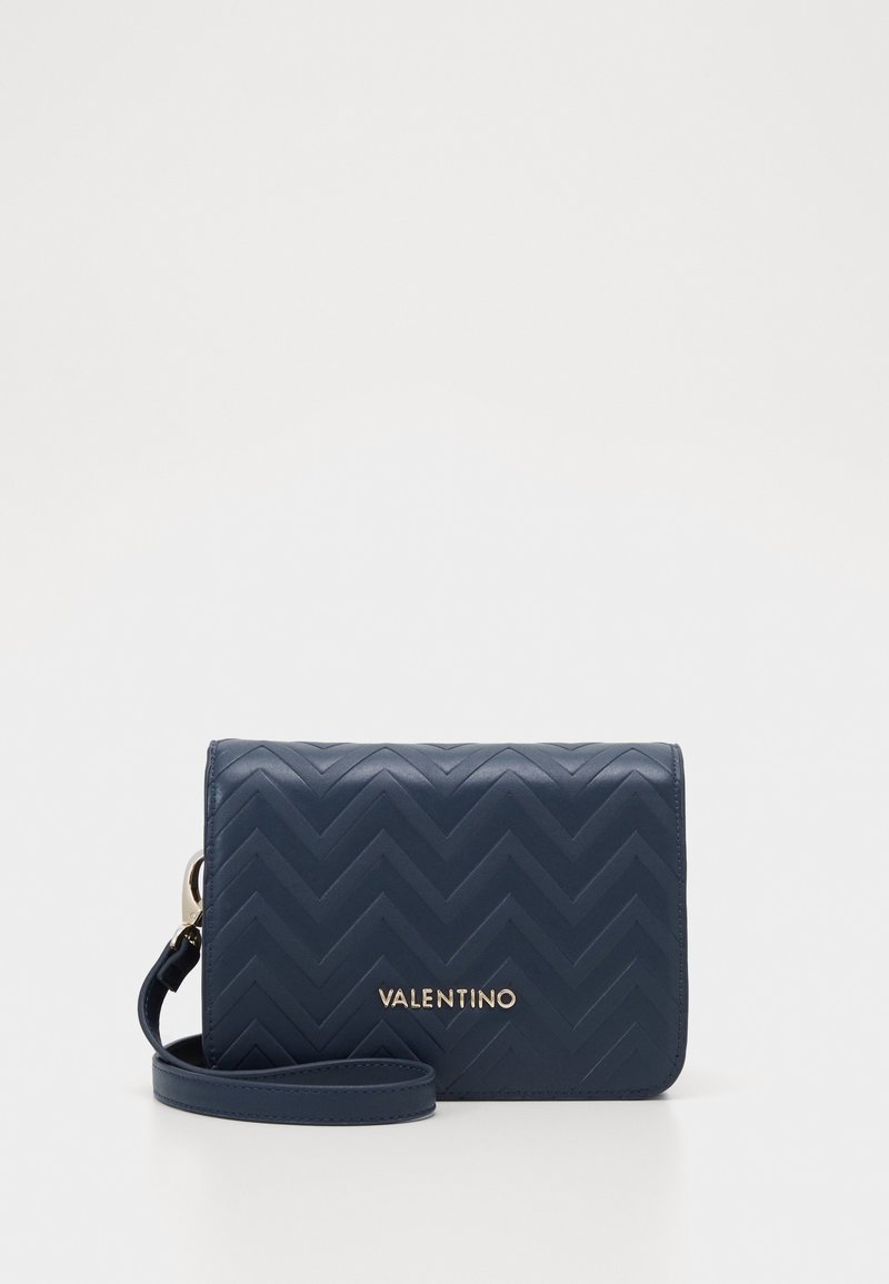 Navy blue quilted crossbody bag with chevron pattern, gold hardware, and detachable strap; features a flat rectangular shape.