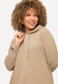 Felpa beige realizzata in tessuto testurizzato con cappuccio, dotata di zip frontale e lacci. Vestibilità rilassata con maniche lunghe.