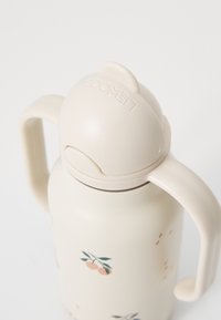 Bouteille d'eau couleur crème avec un couvercle arrondi et deux poignées latérales. Présente des motifs floraux avec de petites pêches et des feuilles vertes.