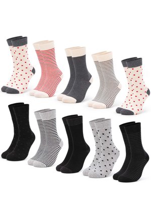 Person trägt weit geschnittene graue Jeans und dunkelgraue Socken mit weißen Zehen und Fersen, setzt einen Fuß nach vorne.