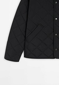 Mustapintainen tikattu takki, jossa on timanttikuvio, napitettava suljin ja piilotetut sivutaskut. Valmistettu kevyestä tekstistä, jossa sileä viimeistely.