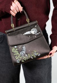 Sac à main en satin noir à la forme structurée, orné d'une broderie loup et lune dans des nuances de gris, vert et bleu. Accents en métal doré.