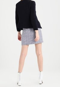 Námořnický blazer, kostkovaná mini sukně v černobílé, doplněná bílými kotníkovými botami se zipem. Hladká tkanina se strukturovaným střihem.