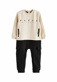 Conjunto de punto en crema y negro que incluye una camiseta de manga larga con el texto "BAKER" y pantalones estilo cargo con dos bolsillos laterales. Textura suave.
