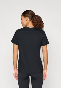 Μαύρο βαμβακερό t-shirt με στρογγυλή λαιμόκοψη και κοντά μανίκια, που διαθέτει λεία υφή και ευθεία τελειώματα στο πίσω μέρος.