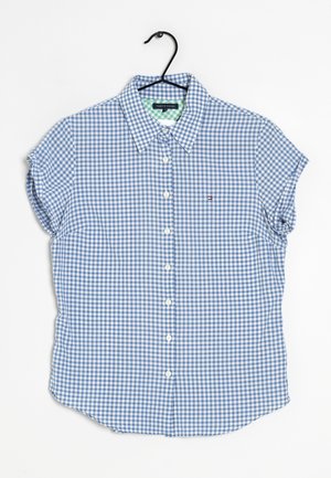 Kortærmet blå og hvid gingham skjorte på sort bøjle på hvid baggrund.