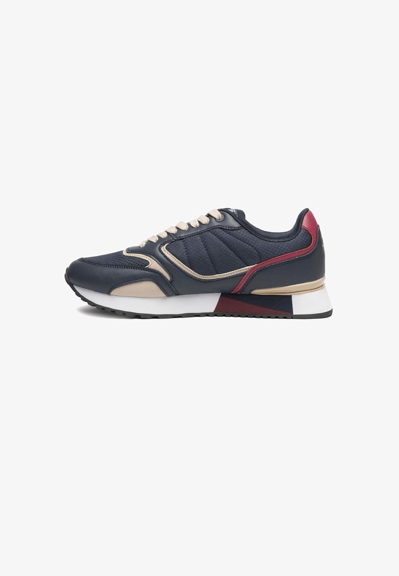 Basket de sport basse bleu foncé avec des accents beige et rouge, semelle blanche et lacets beige, vue de profil sur fond blanc.