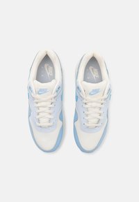 Nike tenisice s gornjim dijelom u svijetloplavoj boji, s mrežastim i sintetičkim premazima, bijelim vezicama i teksturiranom potplatom. Logo prikazan na jeziku.