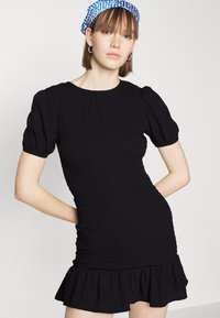 Vestido preto franzido com mangas curtas bufantes e barra godê. Feito de um tecido suave, apresenta uma textura lisa e um design justo.