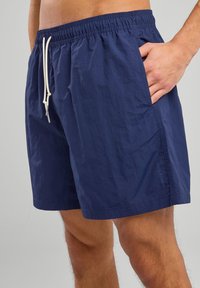Shorts de bain bleu marine en tissu léger, dotés d'une taille élastique avec cordon de serrage réglable et de poches latérales.