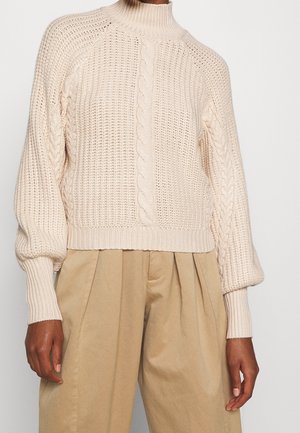 Beiger Strickpullover mit hohem Kragen, Kabelmuster und gerippten Bündchen. Verfügt über ein verkürztes Design und eine offene Webstruktur.