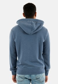 Hætte sweatshirt i et blødt, blåt stof. Har en afslappet pasform, ribbede manchetter og nederdel. Glat tekstur med en kængurulomme og en blød hætte.