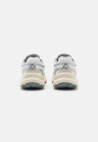 Hvite sneakers med grå aksenter, en teksturert mesh-overdel, tykk skum-mellomsåle og en gummiyttersåle med et mønstret grep.