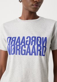 Gray cotton t-shirt featuring bold, inverted blue text reading “Nørgaard” and “GRADAAR” across the chest. Short sleeves and round neckline.