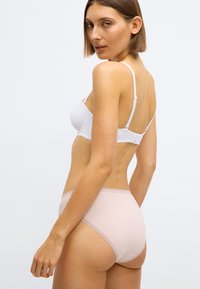 Soutien-gorge blanc et culotte taille haute rose pâle. Le soutien-gorge est doté de bretelles réglables et d'une finition lisse ; la culotte est ornée d'une délicate bordure en dentelle.