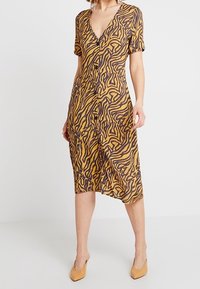 Abito con scollo a V e maniche corte, caratterizzato da un motivo astratto marrone e giallo, con chiusura a bottoni e orlo al ginocchio. Realizzato in tessuto leggero.