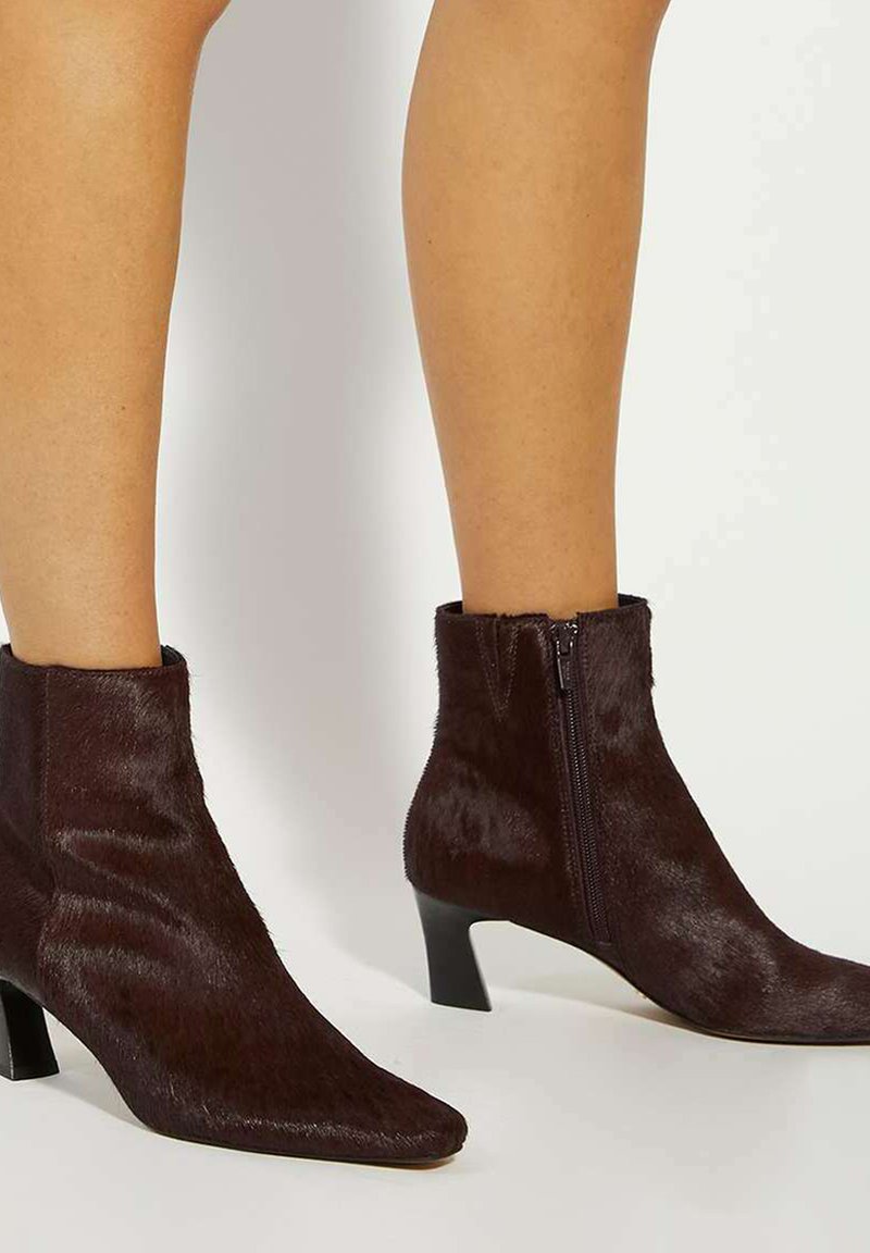 Brown faux fur ankle boots with a pointed toe and zip closure, featuring a low kitten heel and smooth texture.