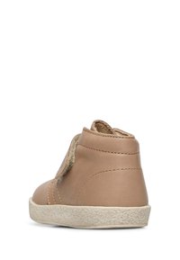 Scarpa alta in pelle color cuoio con suola testurizzata, dettagli con strap in Velcro e design a schienale curvo, caratterizzata da accenti di cucitura minimalista.