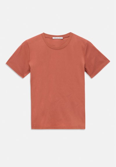 Kort ärmad t-shirt med rund halsringning i dämpad terrakottafärg, utlagd platt mot en vit bakgrund, med en liten varumärkesetikett inuti kragen.