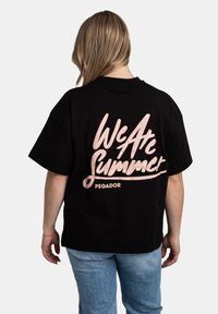 Černé bavlněné tričko s krátkým rukávem a volným střihem. Na přední straně je růžový kurzívní nápis "We Are Summer" a na zadní straně "PEGADOR".