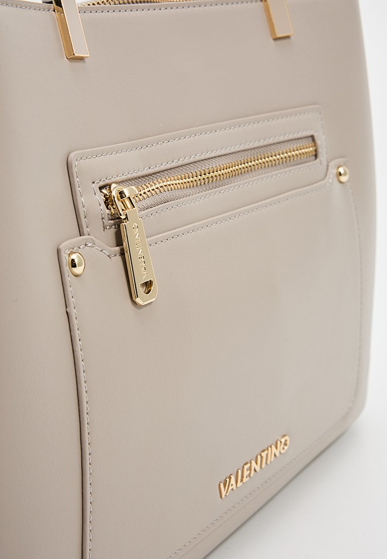 Sac à main en cuir beige avec une poche zippée sur le devant, quincaillerie dorée et logo "VALENTINO". Texture lisse avec de subtils détails de couture.