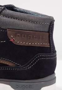 Marineblaue Wildlederstiefel mit grauem Mesh-Kragen, braunen Lederakzenten, kontrastierender Naht und eingeprägtem "bugatti"-Logo an der Seite.