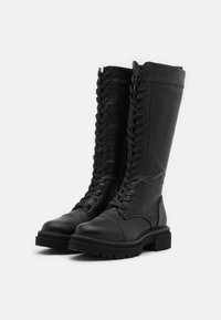 Bottes noires en cuir montantes jusqu'aux genoux avec une fermeture à lacets à l'avant, un bout arrondi et une semelle robuste. Présentent une texture lisse et des coutures renforcées.