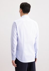 Camicia azzurro chiaro a motivo con maniche lunghe, polsi con bottone e colletto classico. Tessuto liscio con una leggera texture.