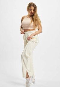 Lys pink cropped tanktop, cremefarvede tapered sweatpants med sideslids, parret med multicolorede sneakers med accenter i blå og pink.