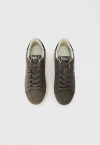 Πράσινα σουέτ αθλητικά παπούτσια με σκούρες κορδόνες και λευκή καουτσούκ σόλα. Διαθέτουν λογότυπο στη γλώσσα και λεία εσωτερική επένδυση. Κλασικός σχεδιασμός χαμηλού τύπου.